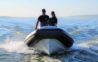 Boating in a GRAND Golden line 13’9″ long luxury rigid inflatable boat (RIB) tender in black; fiberglass hull, outboard motor, steering console, and bow step plate.