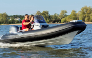 Front angle view of boating in a GRAND Golden line 13’9″ long luxury rigid inflatable boat (RIB) tender in black; fiberglass hull, yamaha 70hp outboard motor, steering console, and bow step plate.