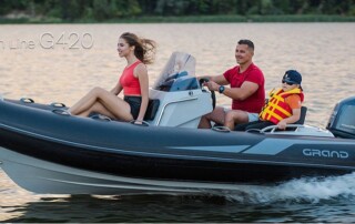 Family boating in the GRAND Golden line 13’9″ long luxury rigid inflatable boat (RIB) tender in black; fiberglass hull, steering console, 70 HP outboard motor and bow step plate.