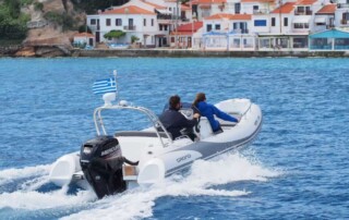 Boating rear view of a GRAND golden line 16’3″ long luxury rigid inflatable boat (RIB) in white & dark gray with a fiberglass hull, step ends, bow step, seating, & console.