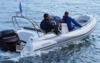 Boating rear side view of a GRAND golden line 16’3″ long luxury rigid inflatable boat (RIB) in white & dark gray with a fiberglass hull, step ends, bow step, seating, & console.