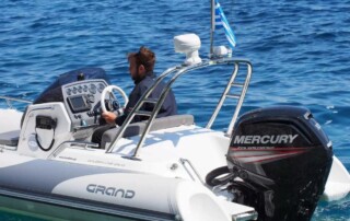 Rear view of a GRAND golden line 16’3″ long luxury rigid inflatable boat (RIB) in white & dark gray with towing navigation arch, outboard motor, steering console with seat, and step ends.