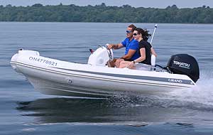 GRAND GOLDEN LINE 11’10” RIB tender with fiberglass hull, step ends, and steering console, rigged with a Tohatsu outboard motor.